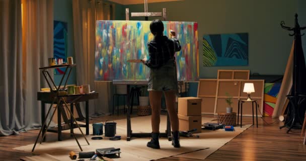 Mulheres artista está pintando uma pintura a óleo abstrata, ela está olhando para os resultados de — Vídeo de Stock