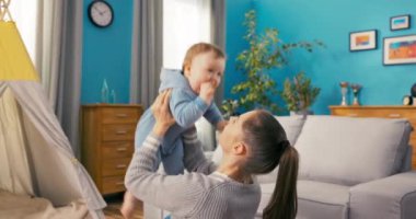 Genç anne yere oturur, bebeği kollarının altından tutar ve büyütür.