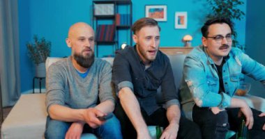 Bir grup arkadaş oturma odasındaki kanepede oturuyor ve ellerinde bira var.