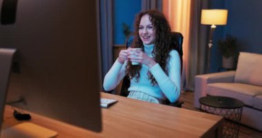 İşten sonra yorgun ve güzel bir kız akşamları bilgisayar ekranının önünde dinleniyor.