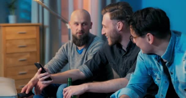 Tre uomini si rilassano sul divano del soggiorno la sera di fronte — Video Stock