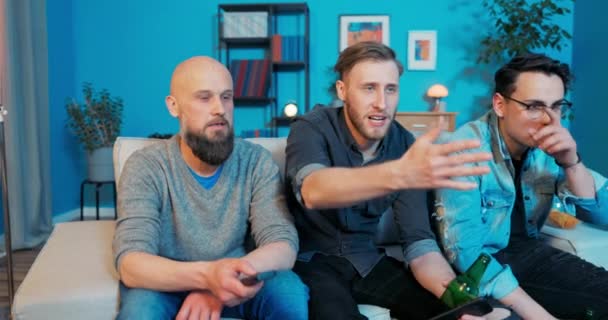 Группа приятелей, сидящих на диване в гостиной вечер с пивом в руке впереди — стоковое видео