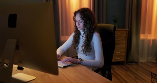 Студент сидит перед экраном компьютера поздно вечером, пишет диплом бакалавра, — стоковое видео