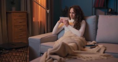 Güzel esmer, kıvırcık saçlı. Akşamları kanepede dinleniyor. Oturma odasında içiyor.