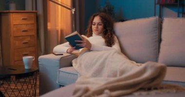 İşten sonra yorgun bir kadın akşamları lamba ışığında dinlenir.