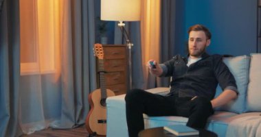 Gülümseyen bir adam işten sonra rahat, rahat oturma odasında dinleniyor.