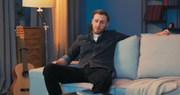 한 남자가 저녁에 집에서 일 한 후 편안 한 거실에서 휴식을 취한다. 미국 의 — 비디오