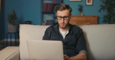 Öğrenci akşamları oturma odasındaki kanepede oturur dizüstü bilgisayarın önünde ayakta durur.