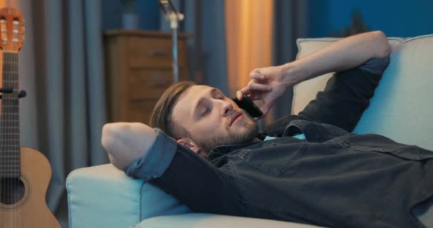 Gömlekli adam işten sonra kanepeye uzanıp dinleniyor, yorgun, uykulu, yorgun ve yorgun. — Stok video