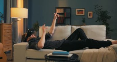 Adam işten sonra kanepede oyun gözlüğü takarak rahatlıyor. Sanal gerçeklik.