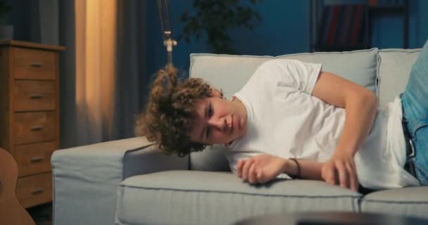 Adolescente stanco torna a casa dal lavoro, la scuola, si stende comodamente sul divano in — Video Stock