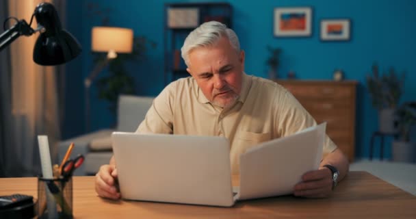 Un anciano hombre de negocios lee documentos de la compañía. Hombre riendo, feliz con los logros de la compañía. Jefe sonriente leyendo — Vídeos de Stock