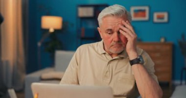 Yorgun, çökmüş, istifa etmiş, dalgın yaşlı bir adam dizüstü bilgisayarın, bilgisayarın ve