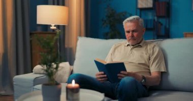 Olgun bir adam oturma odasındaki kanepede mumla dinlenir..