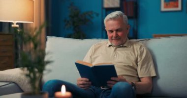 Kanepede oturan gülümseyen mutlu yaşlı adamın portresi. Yaşlı adam kameraya bakıyor.