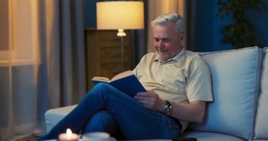 Kanepede oturan gülümseyen mutlu yaşlı adamın portresi. Yaşlı adam kameraya bakıyor.