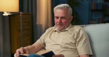 Kanepede oturan gülümseyen mutlu yaşlı adamın portresi. Yaşlı adam kameraya bakıyor.