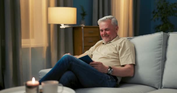 Portret uśmiechniętych starszych mężczyzn siedzących na kanapie patrzących w kamerę — Wideo stockowe