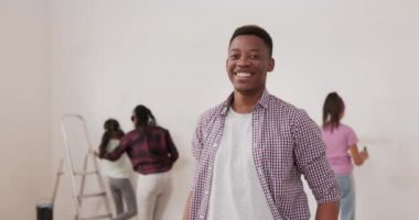 Ekose gömlekli, gülümseyen bir adam karısıyla birlikte bir apartman dairesini yeniliyor.