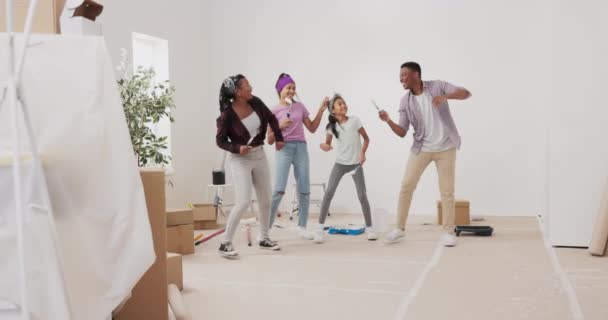 Szalona szczęśliwa rodzina malowanie ścian z białą farbą ze szczotkami, tańczą w środku — Wideo stockowe