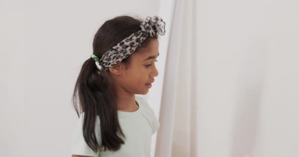 Onnellinen pieni tyttö käsissään pitämällä rullan valkoinen maali, huolellisesti yrittää — kuvapankkivideo