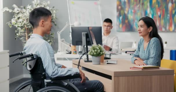 En anställningsintervju med en handikappad man i rullstol, vacker kvinna i asiatisk koreansk skönhet — Stockvideo
