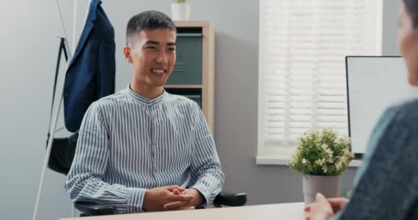 Людина з обмеженими можливостями, одягнена в розумну блакитну смужку, сидить за столом у корпоративному офісі в — стокове відео