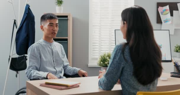 Gehandicapte man gekleed in slim blauw gestreept shirt zit aan het bureau in het kantoor in — Stockvideo