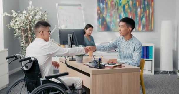 Két férfi találkozik a céges irodában reggel, hogy interjút készítsenek a fogyatékos fiúval, aki tolószékben érkezik. — Stock videók