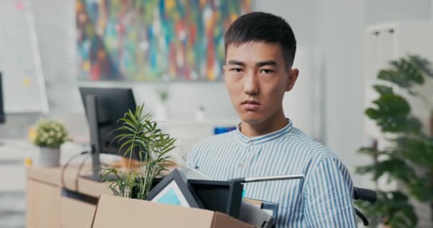 Αναπήρων φιλόδοξος άνθρωπος σε πουκάμισο με ασιατική κορεατική ομορφιά κάθεται σε αναπηρική καρέκλα στο γραφείο στο — Αρχείο Βίντεο
