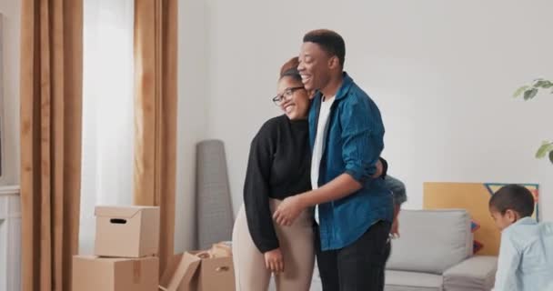 Manželé se radostně objímají poté, co se oba přestěhují, stojí v obývacím pokoji — Stock video