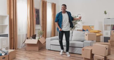 Oturma odasının ortasında yeni bir dairede bir adam dans ediyor.