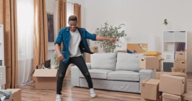 Neşeli yakışıklı adam yeni dairede zıplayan danslar, karton kutular