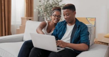 Evli bir çift, taşındıktan sonra yeni evlerindeki kanepede oturuyor.