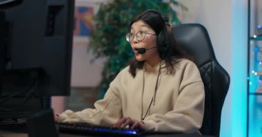 Profesyonel Oyuncu Kız online video oyunu kazanarak ellerini sevinçten yumrukluyor zafer işareti olarak genç hayranlarına kulaklık takıyor, arka plan neon başlıklı renkler