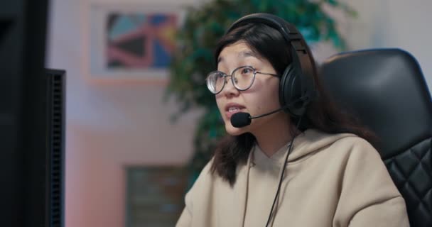 Amateur girl learns to play games on computer, talks through headset with team members, smiles, sudden turn of events woman loses round, disqualification, covers face with hands she is angry sad — Vídeos de Stock