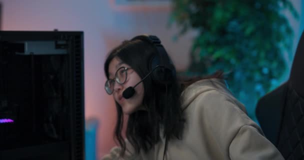 Eljegyzett játék lány ül a szobában, a számítógép monitor előtt professzionális játék berendezések fejhallgató mikrofonnal beszél riválisok harcol győzelem stratégia sötét szoba led fények — Stock videók