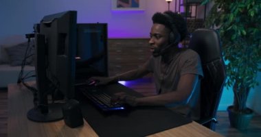 Profesyonel profesyonel video oyuncusu bilgisayarda oynarken oyunu kaybetti, kalbi kırıldı, hayal kırıklığına uğradı, utandı, yüzü elle kaplandı, oda neon ışıklarıyla aydınlatıldı.