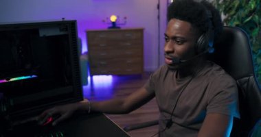 Kulaklıklı, profesyonel bilgisayar oyuncusu, online nişancı oyunlarının ustası Afro adamın yüzüne yakın çekim. Öğrenci, takım üyeleriyle sohbet ediyor ve galibiyet stratejisini hazırlıyor.