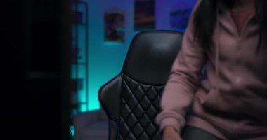 Popüler kız streamer odaya ışıklarla girer, bilgisayarın önünde sandalyeye oturur kulaklıkları takar, video oyunları oynayan genç bir kadın bir oyunu canlı yayında izlediği hayranlarını selamlar.