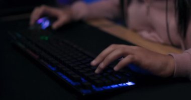 Profesyonel arka ışıklandırma klavyesinde çalan genç kızın yakın çekimleri, öncü ışıklandırma, bilgisayar çalan kadın
