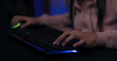 Profesyonel bir klavyede çalan genç bir kızın elleri, öncü ışıklandırma, bir bilgisayar oyununda oynayan bir kadının yüzüne geçiş gülümsemesi internet şampiyonası oyununa odaklanmış.