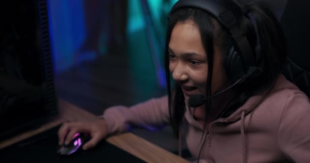 Τοπ σουτ από το πρόσωπο του gamer girls. Teenage κορίτσι είναι παθιασμένη με τα βιντεοπαιχνίδια, παίζει υπολογιστή, ενώ χαμογελά, έχει ακουστικά για να μιλήσει με τα μέλη της ομάδας σε απευθείας σύνδεση, εικονικό κόσμο — Αρχείο Βίντεο