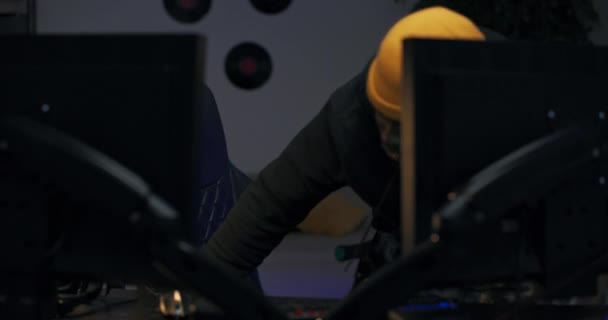 Популярний стример заходить в кімнату, освітлену світлодіодними ліхтарями, сідає на стілець перед комп'ютером і одягає навушники, чоловічий відеогравець вітає фанатів, для яких він в прямому ефірі транслює онлайн-ігровий процес — стокове відео