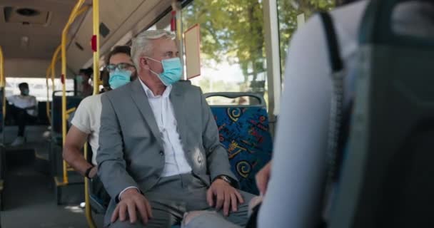 An elderly businessman in a suit, with gray hair and a protective mask over face — ストック動画