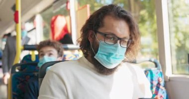 Uzun saçlı, kalın sakallı, maske takan bir adam.