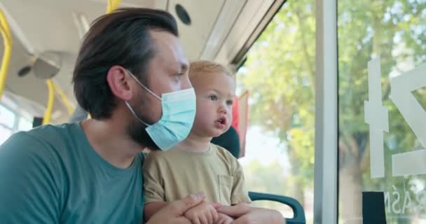 Un padre está viajando en autobús con su lindo hijo pequeño en el regazo. El hombre — Vídeos de Stock