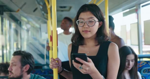 Bus staat bij de bushalte in het centrum vrouw met bril met behulp van het openbaar vervoer houdt — Stockvideo