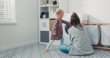 Kadın, küçük çocukla çamaşır odasında, banyoda vakit geçiriyor, doğum iznindeyken ev işlerini yapıyor, kızına bakıyor, çamaşır makinesini nasıl kullanacağını gösteriyor.