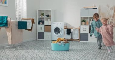 Kardeşler çamaşır odasında, banyoda, çamaşır kâsesinin ve çamaşır makinesinin etrafında koşuşturuyor, çocuklar kurutucudan çıkarılmış kazaklar giyiyorlar.